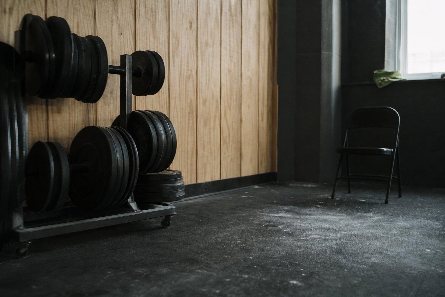 An empty backstage warm-up room with iron plates racked and chalk dust on the floor